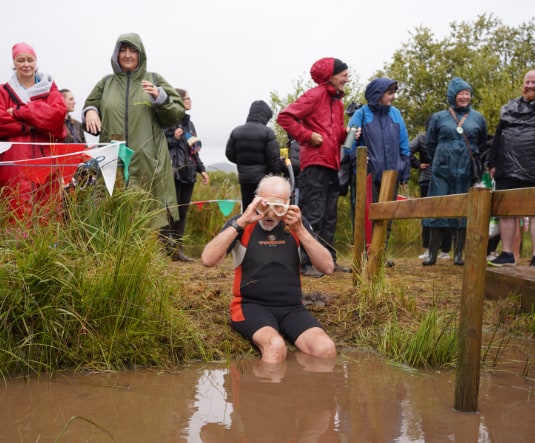 A snorkeller adjusting their goggles in the bog as a crowd looks on in the rain