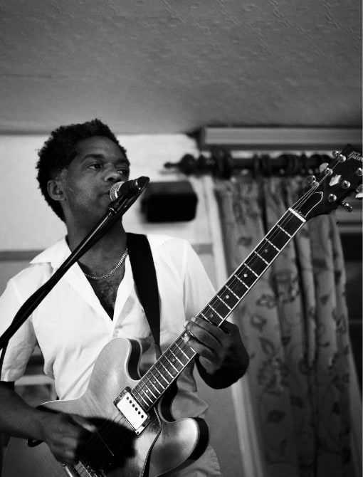 Black and white portrait of a guitarist singing into a microphone