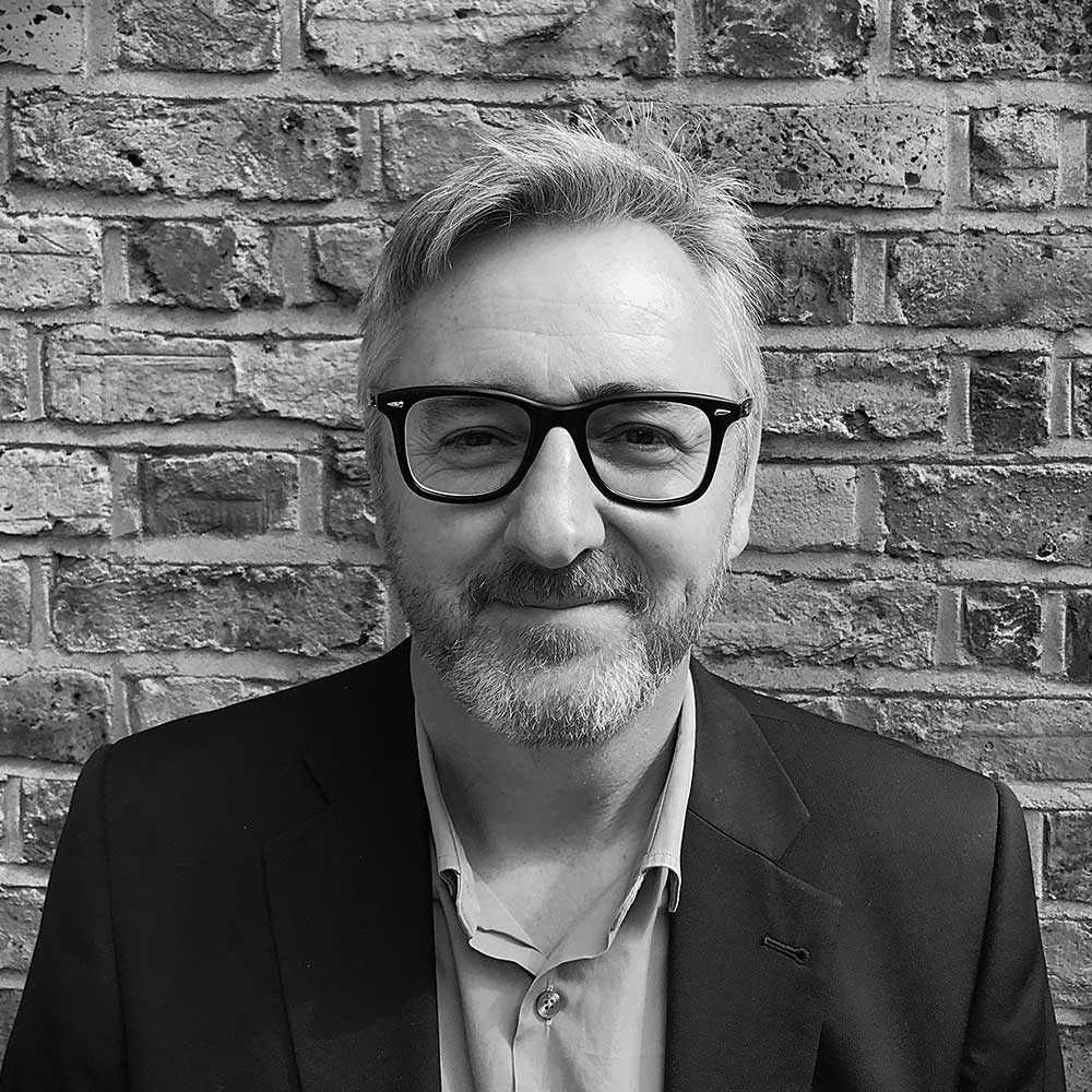 Black and white portrait of Irfon, co-founder, against a brick wall
